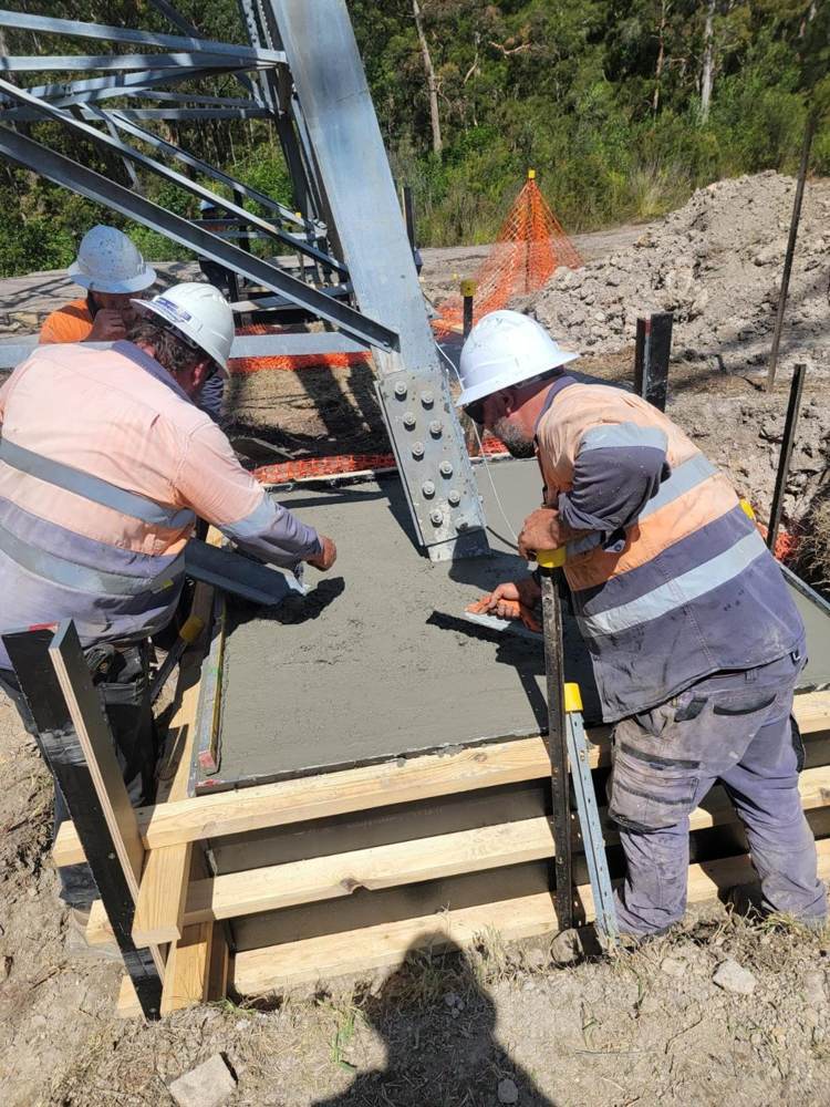 Crew finishing a new footing around a tower leg